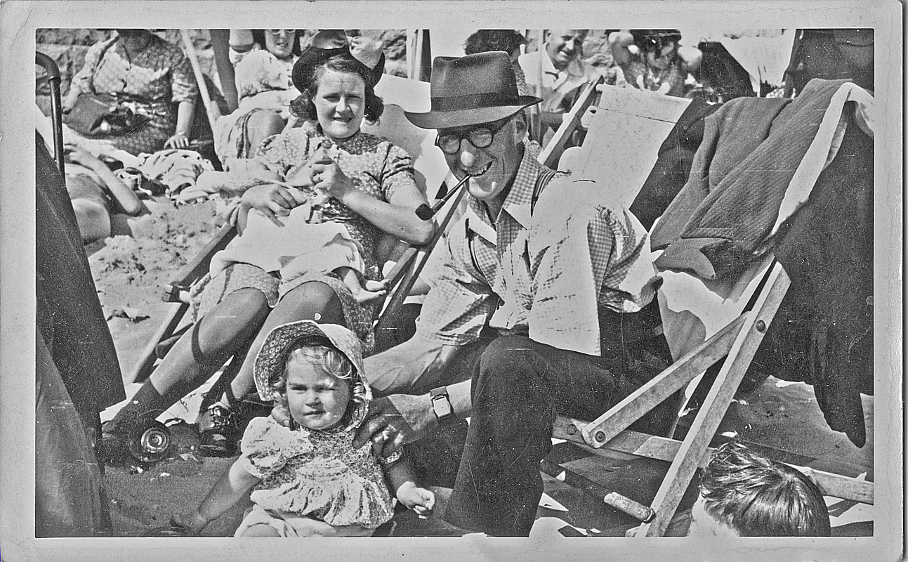 old photograph of family standing in forest beside wooden barn