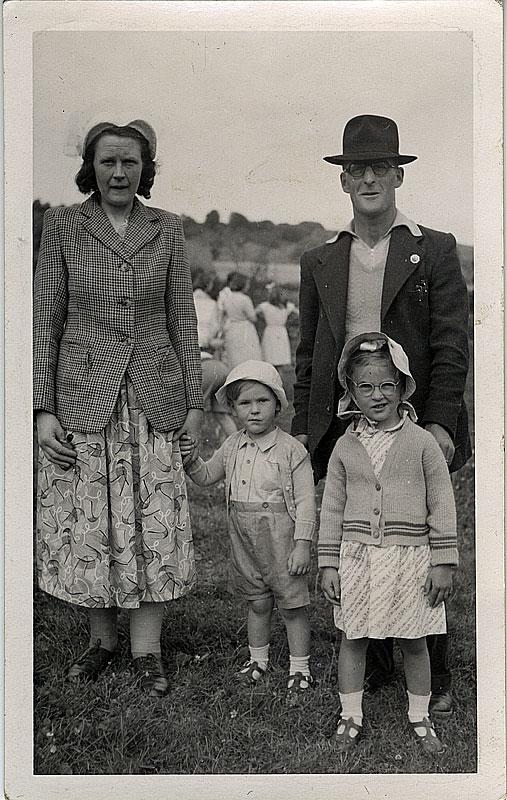 old photograph of family standing in forest beside wooden barn