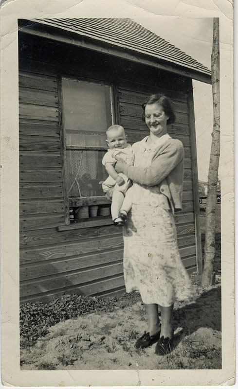 old photograph of family standing in forest beside wooden barn