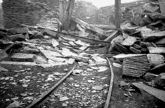a ruined mine, with tumbled stone walls and narrow gauge track
