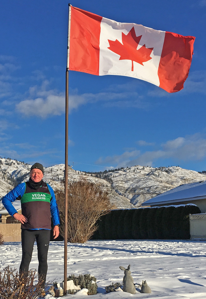 Ralph Mills standing beside a Candian Flag in a snow-covered garden